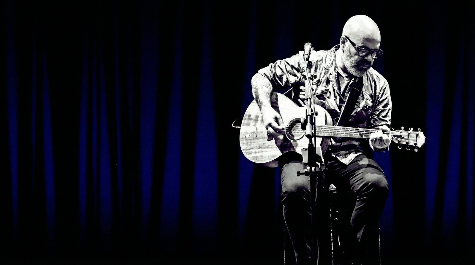 Live acoustic guitarist singer performing on stage in Riviera Maya — black and blue lighting