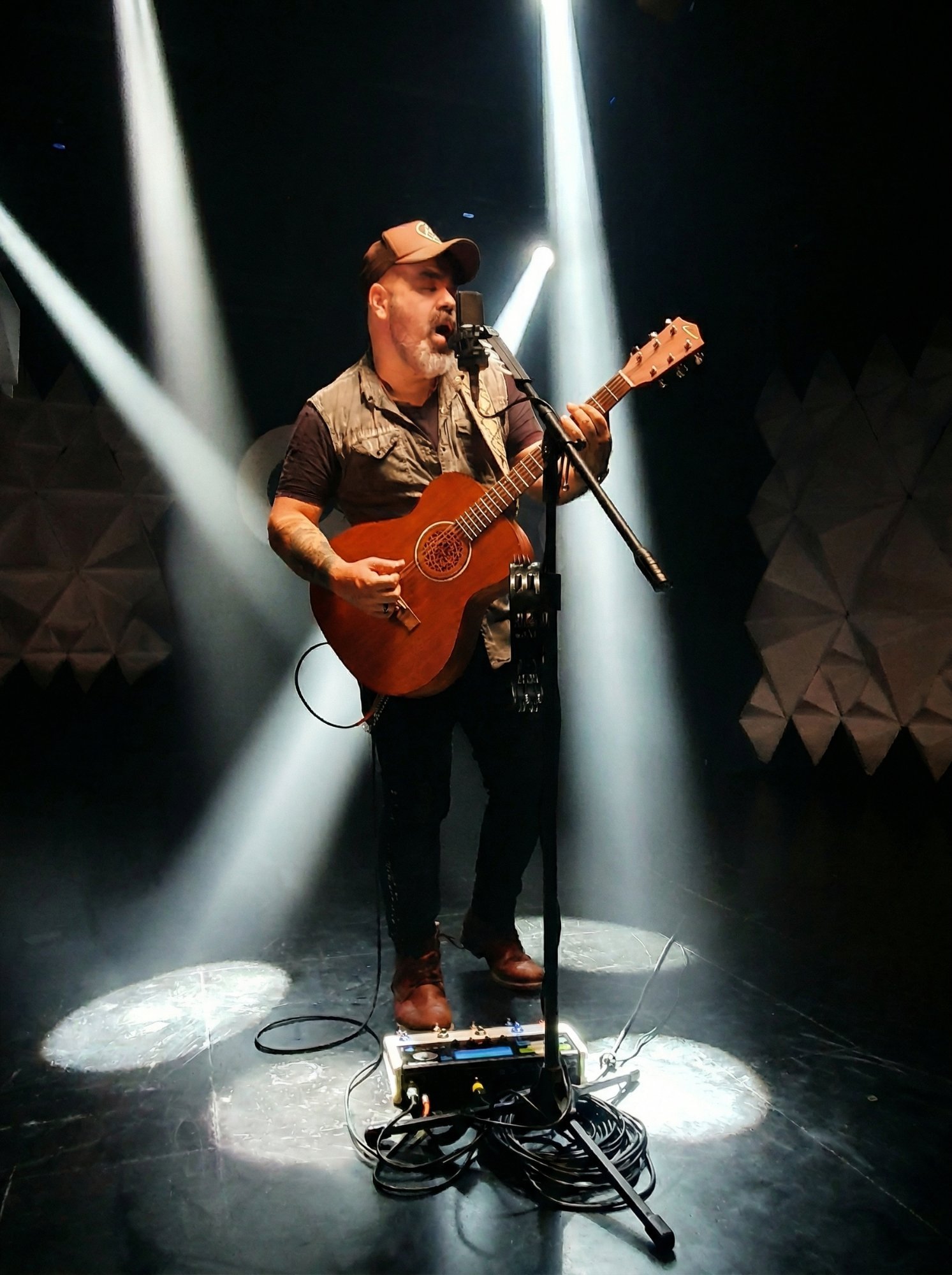 Rodo Acústico performing live on stage with loop pedal and spotlights